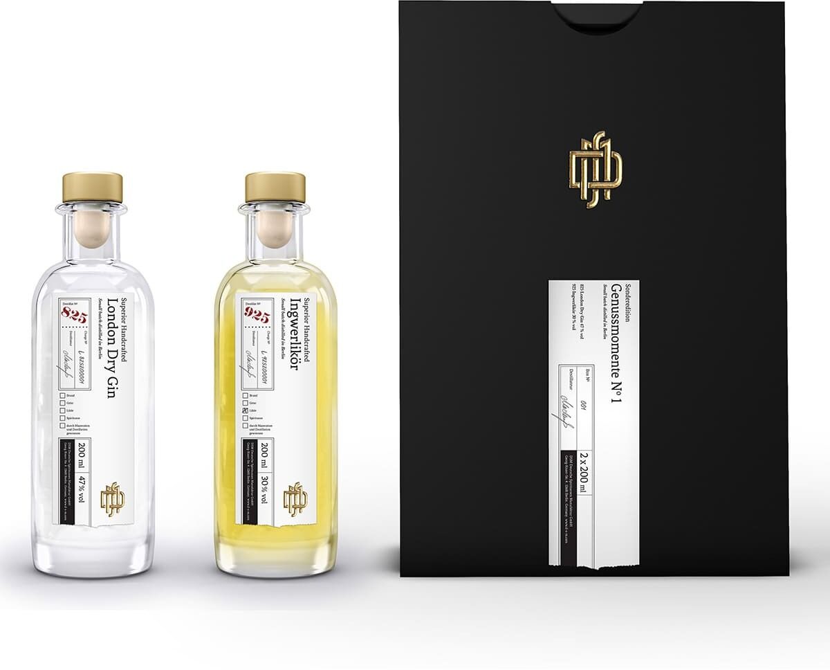 ZEIT-Sonderedition »Genussmomente No 1« Geschenkset bestehend aus einer schwarzen Verpackung mit goldenem Emblem und zwei Flaschen eines exklusiven Gins und Likörs, einer halbdurchsichtigen Flasche und einer gelben Flasche, beide mit weißen Etiketten.