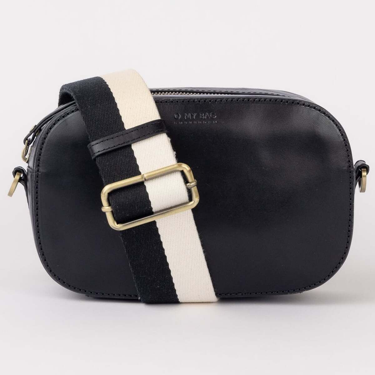 Eine kleine, moderne Umhängetasche namens Maya mit abgerundeter Form, schwarzem Korpus und verstellbarem Schulterriemen in Schwarz und Weiß sowie goldfarbener Schnalle vor hellem Hintergrund. Die Tasche eignet sich ideal für den Alltag oder besondere Anlässe.