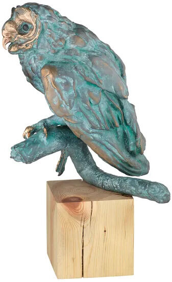 Bronzeskulptur einer detailreichen Eule mit grüner Patina auf einem Ast sitzend, montiert auf einem hellen Holzsockel; künstlerisches Wohnaccessoire oder Dekorationsobjekt.