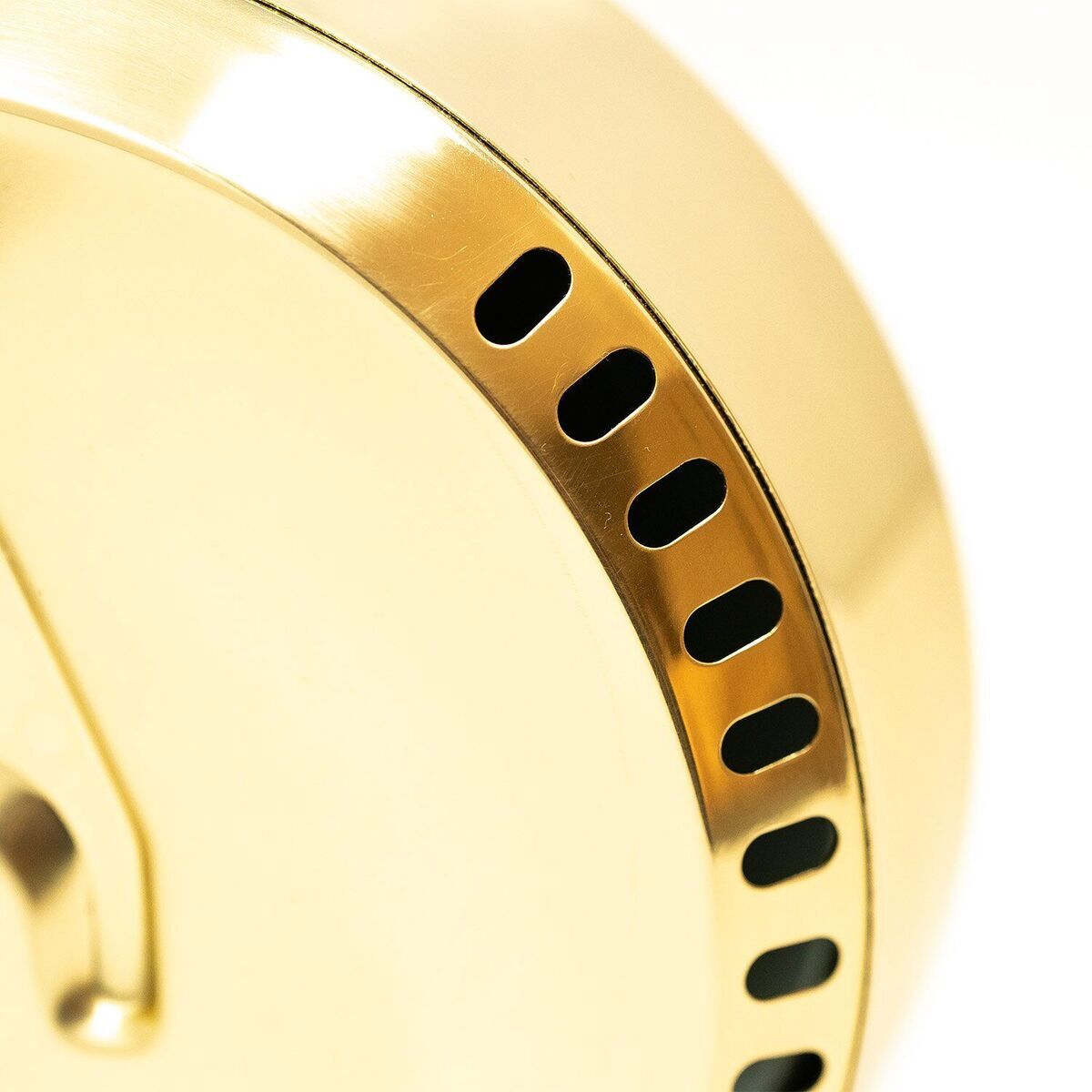 Nahaufnahme eines goldfarbenen Artikels aus dem ZEIT-Sonderedition »POLAR« Set. Das Bild zeigt ein modernes und elegantes Design mit kleinen Löchern, die einem dekorativen Muster gleichen.