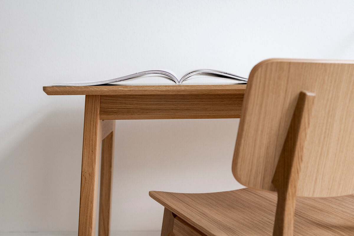 Ein minimalistischer Schreibtisch aus Eiche namens 'Freya' mit passendem Stuhl, dargestellt vor einer weißen Wand.
