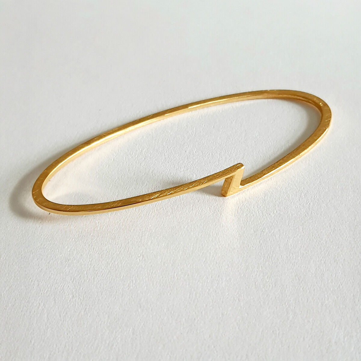 Goldener, minimalistisch designter Armreif der ZEIT-Jubiläumsedition auf weißem Hintergrund.