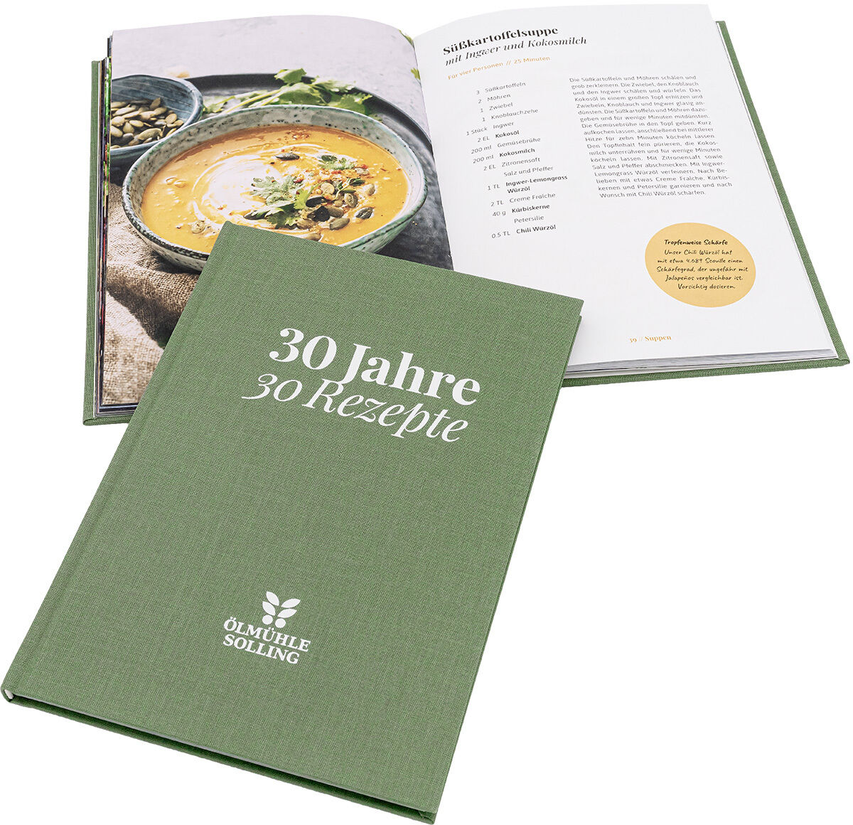 Das Bild zeigt das Kochbuch „30 Jahre 30 Rezepte“ der Ölmühle Solling. Der grüne Hardcover-Einband liegt vorne, im Hintergrund sieht man das aufgeschlagene Buch mit einem Rezept und einem Foto einer Suppe in einer Schale. Das Design wirkt schlicht und hochwertig.