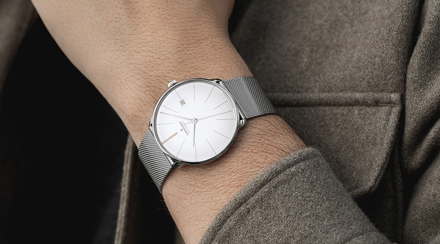 Junghans Armbanduhr mit silbernem Mesh-Armband und weißem Zifferblatt am Handgelenk einer Person