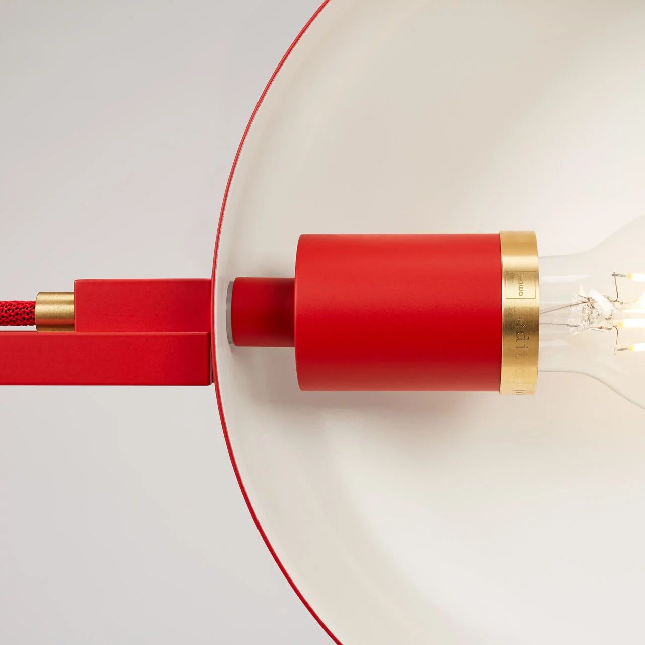 Nahaufnahme einer Designer-Stehleuchte »schliephacke« von mawa design in limitierter Edition. Das Lampengehäuse besteht aus kräftig rotem Aluminium mit feinem Goldring; innen ist der Reflektor mattweiß. Sichtbares Textilkabel in Rot, Glühbirne erkennbar, hochwertige Verarbeitung, stilvoll und modern.