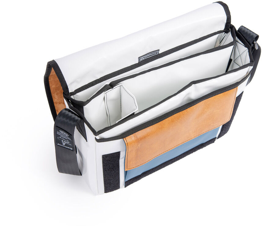 Bild einer ZEIT-Tasche »Kasten« mit einem schwarzen Gurt. Die Tasche ist mehrfarbig mit den Farben Schwarz, Weiß, Braun und Blau. Die Tasche hat ein schlichtes aber stilvolles Design und besitzt mehrere Fächer.