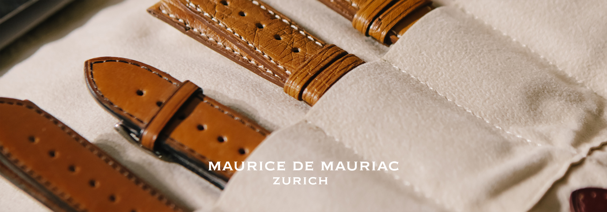 Eine sauber geordnete Auslage von Lederarmbändern in verschiedenen Brauntönen mit perforierten Mustern, beschriftet mit „Maurice de Mauriac, Zürich“.