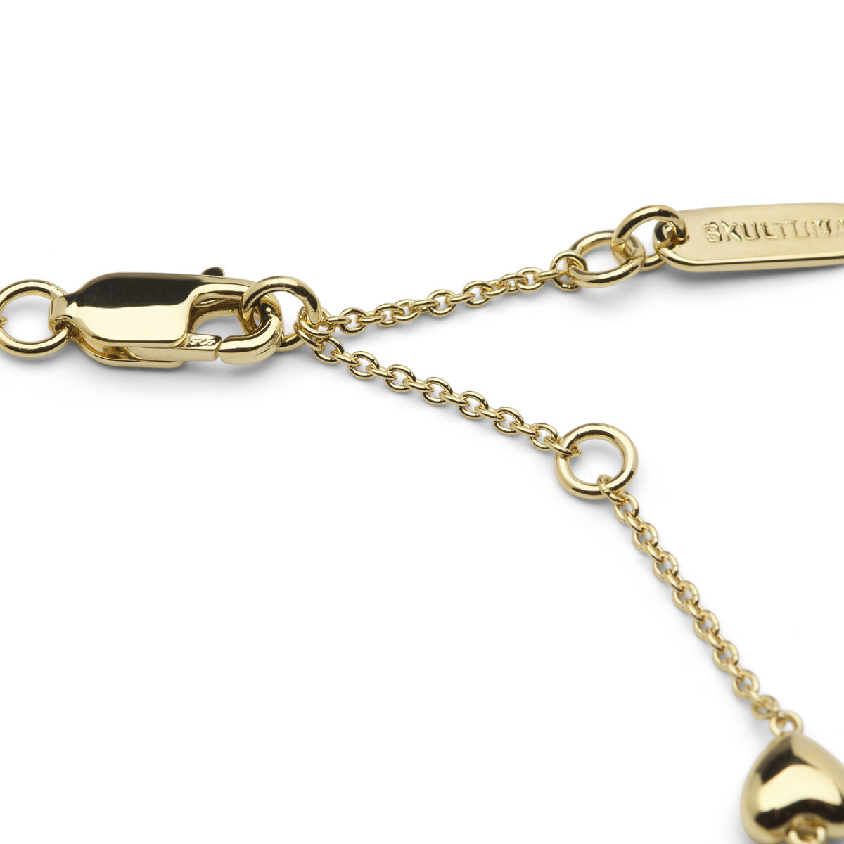 Detailaufnahme eines eleganten goldfarbenen Armbands mit Kettenverschluss und Anhänger in Herzform. Das Schmuckstück liegt auf weißem Hintergrund.