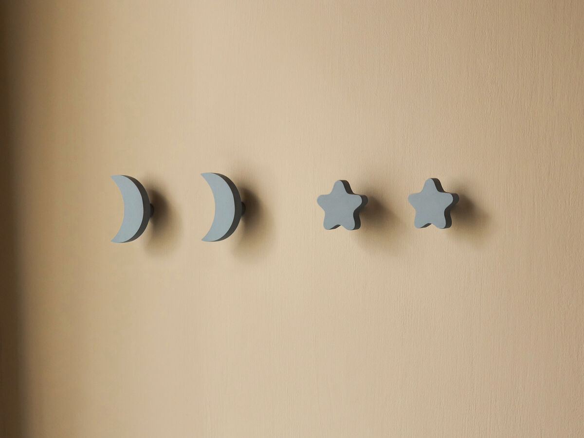 Vier Wandhaken in Form von zwei Sternen und zwei Monden, in blauer Farbe vor einer beige gestrichenen Wand montiert.
