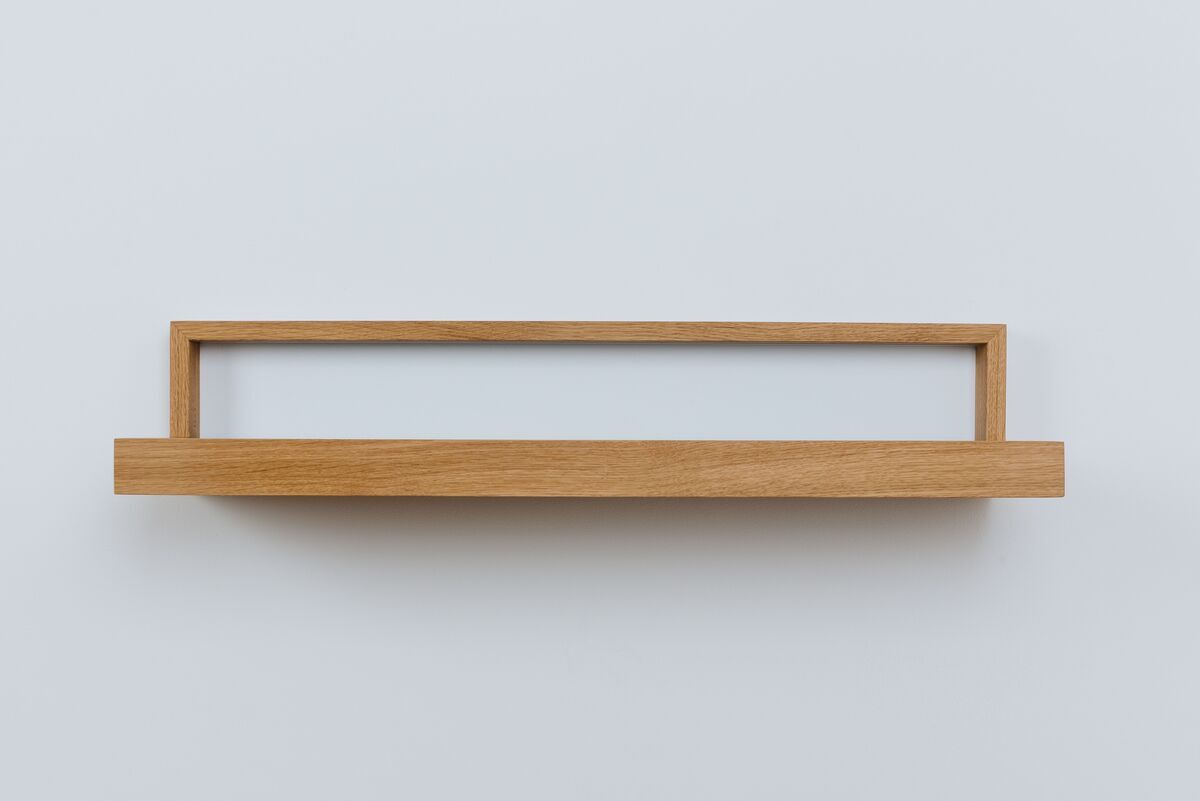 Ein minimalistisch gestaltetes Ablagebord in Anthrazit, mit einer offenen Holzstruktur und schlichtem Design, an einer weißen Wand montiert.