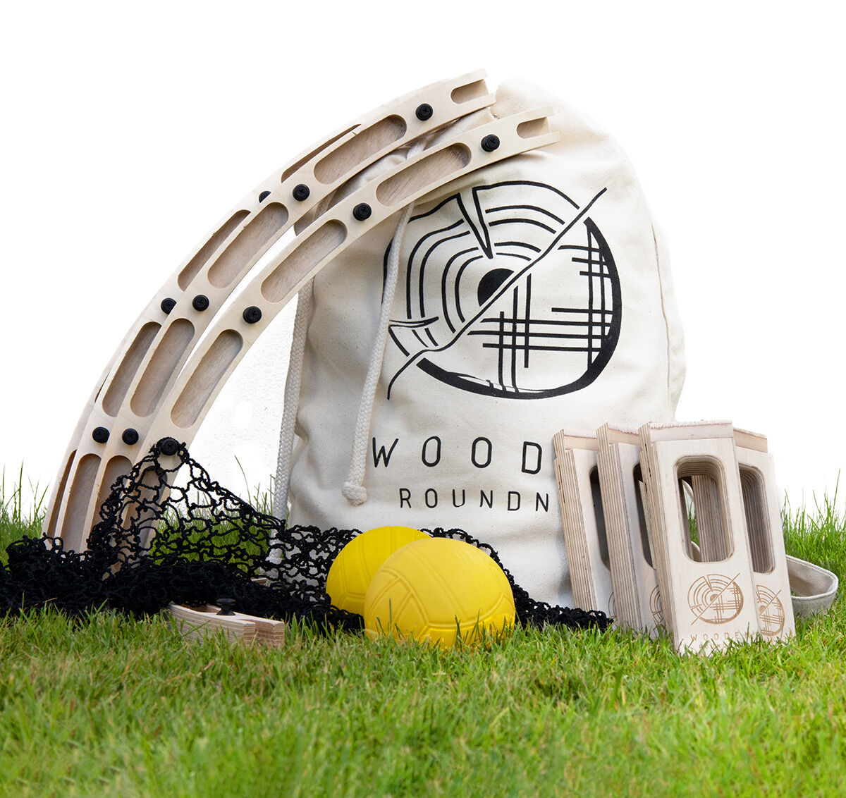 Ein Holz-Roundnet-Spiel auf grünem Gras, bestehend aus einem Netz, zwei gelben Bällen, hölzernen Rahmen und einer weißen Tasche mit der Aufschrift 'Wooden Roundnet'.