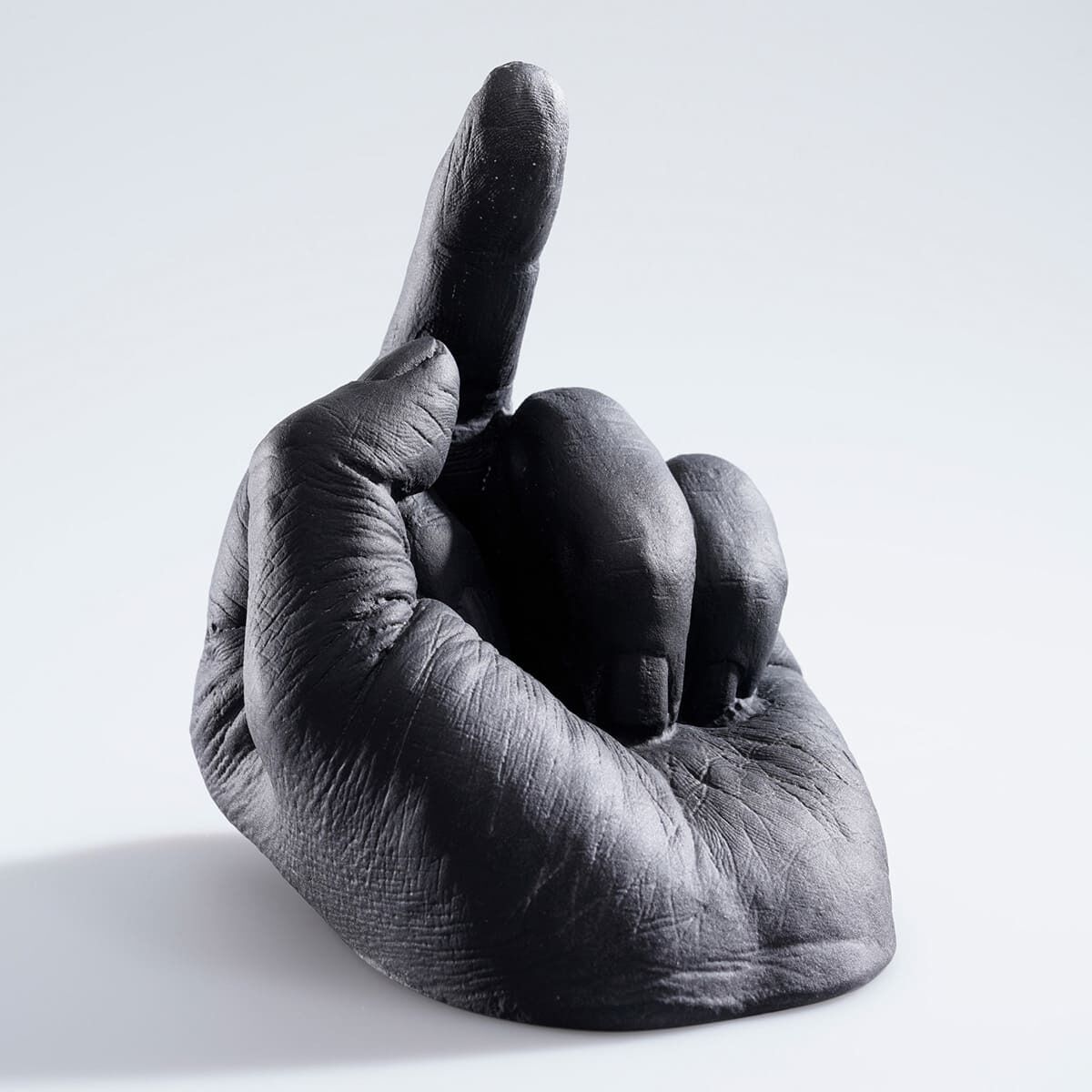 Schwarze Hand in Glas, die einen erhobenen Zeigefinger zeigt. Die Skulptur hat eine detaillierte Textur und einen minimalistischen Stil. Hintergrund ist weiß und schattiert.