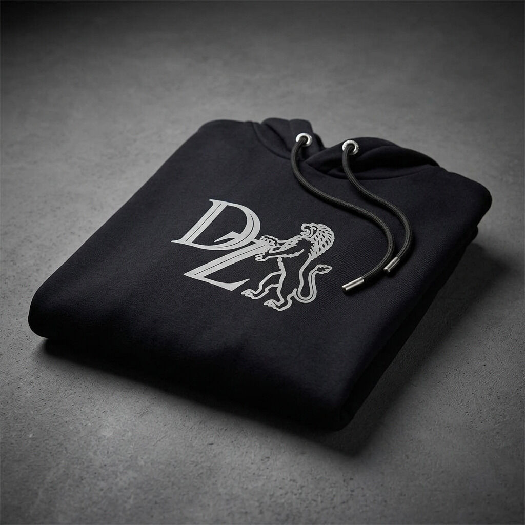 Schwarzer Hoodie der ZEIT-Kollektion, sorgfältig zusammengelegt, auf grauem Untergrund. Vorne mittig ist ein graues Schaumprint-Logo mit einem Löwen und großen Buchstaben 'ZEIT' zu sehen. Metallene Kordelenden und Ösen unterstreichen das hochwertige Design.