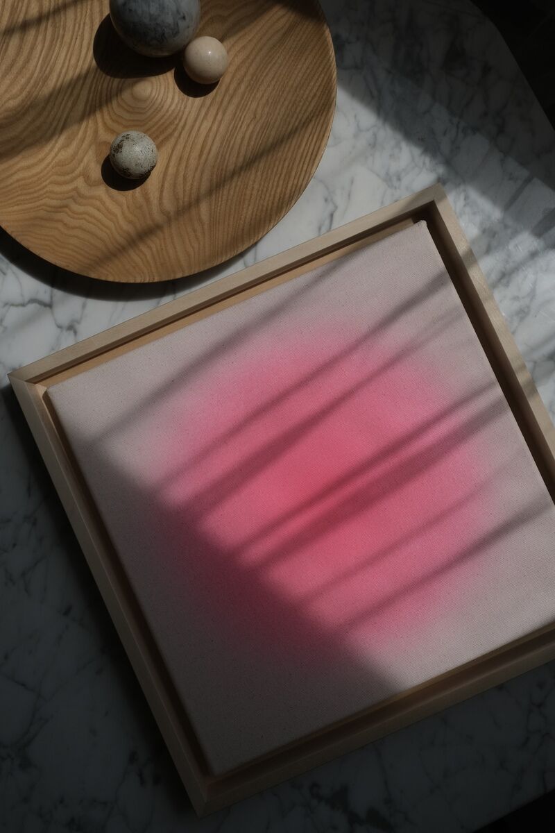 Ein Kunstbild mit dem Titel 'ZEIT-Sonderedition Sorbet »Pink«' (30x30cm), das eine rosa Farbverlauf in der Mitte hat und von einem Holzrahmen umgeben ist. Das Bild liegt auf einer weißen Marmoroberfläche, die von natürlichen Materialien und Schatten umgeben ist.