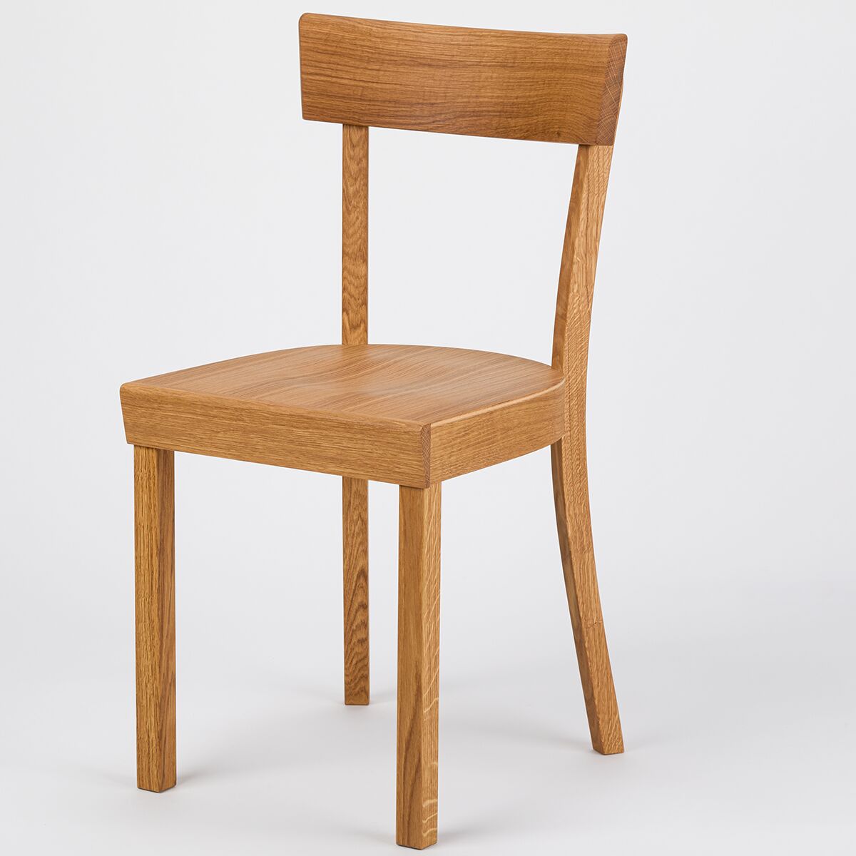 Ein moderner Küchenstuhl aus geölter Eiche, bekannt als ZEIT Sonderedition »Frankfurter Küchenstuhl«. Der Stuhl besitzt eine leicht geneigte Rückenlehne sowie eine glatte, rechteckige Sitzfläche, beide aus demselben natürlichen Holz gefertigt. Der Stuhl steht vor neutralem Hintergrund, wodurch die Holzmaserung und das schlichte Design im skandinavischen Stil besonders zur Geltung kommen.