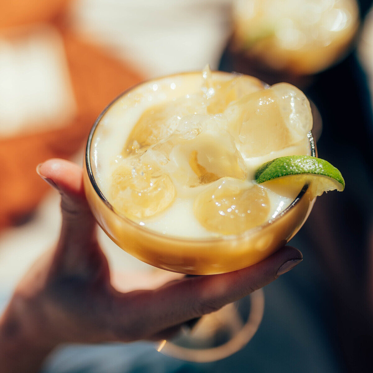 Nahaufnahme eines Cocktailglases mit »Premium Eierlikör« von Rübbelberg, verfeinert mit Eiswürfeln, Bananenscheiben und einer Limettenscheibe. Das Getränk wirkt cremig und frisch, ideal für sommerliche Feste oder besondere Anlässe.