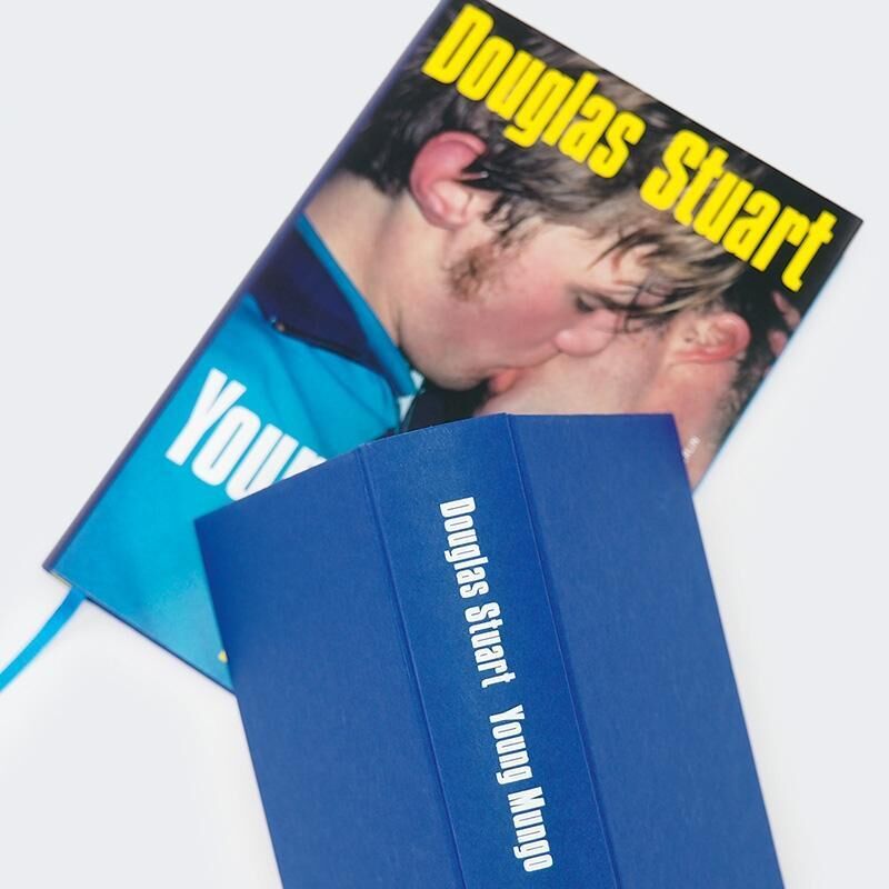 Das Bild zeigt das Buch 'Young Mungo' von Douglas Stuart. Das Cover zeigt zwei junge Männer in Nahaufnahme beim Küssen. Das Buch hat ein blauen Hintergrund mit einem gelben Text.