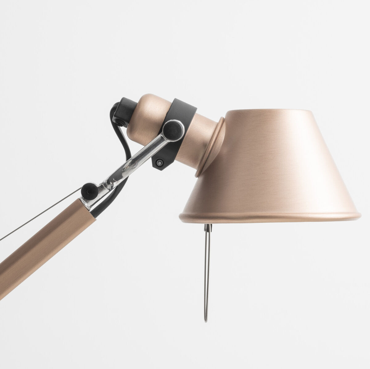 Nahaufnahme einer modernen Designer-Schreibtischlampe 'Artemide Tolomeo Micro' in bronzefarbener Ausführung, mit verstellbarem Schwenkarm und minimalistischen Designelementen, vor einem weißen Hintergrund.