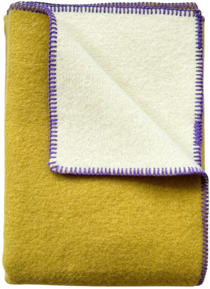 Foto einer zweifarbigen Decke namens 'Doubleface', mit einer gelben Seite und einer cremeweißen Seite mit violetten Rändern, gefaltet dargestellt.