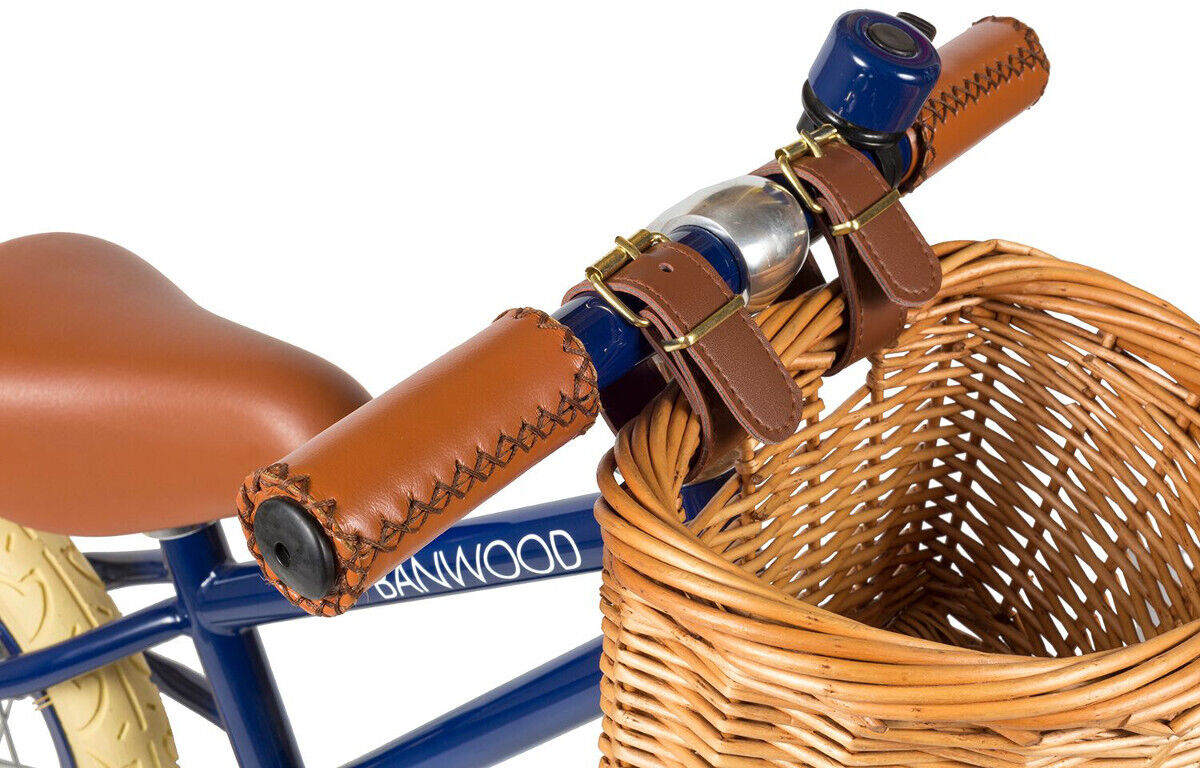 Ein Retro-Laufrad mit einem braunen Fahrradsattel und einem geflochtenen Körbchen vorne. Das Laufrad hat einen blau gestrichenen Rahmen und beige Reifen.