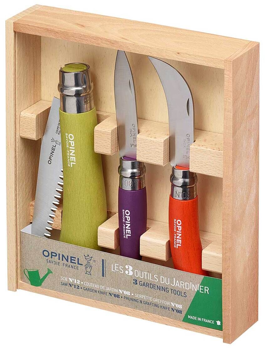 Ein Garten-Set in einer Holzkiste von der Marke Opinel. Das Set umfasst eine Säge, eine Gartenschere mit lila Griff und eine mit orangem Griff. Die Werkzeuge sind sauber und ordentlich in der Holzkiste aufbewahrt.