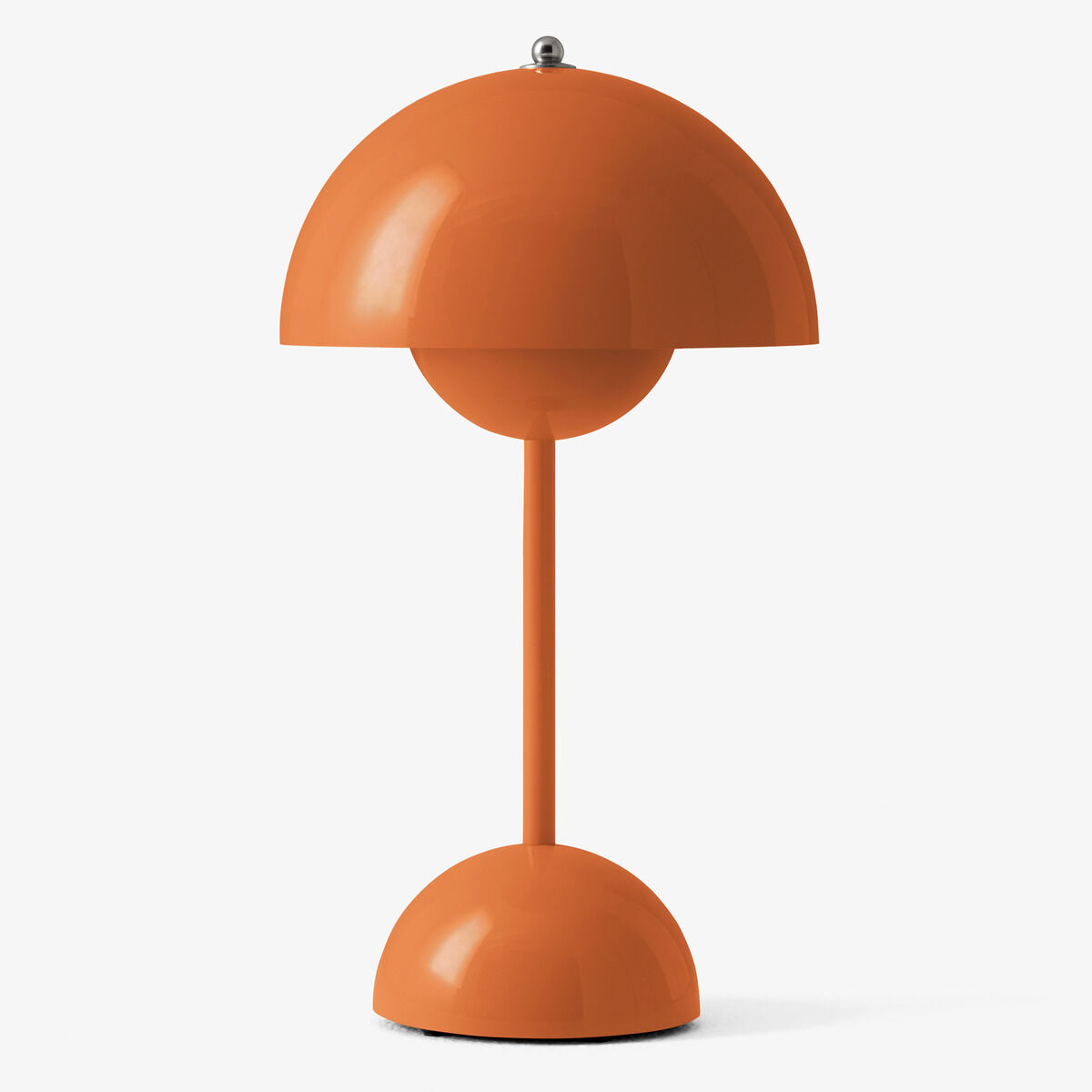 Die Flowerpot VP9 Tischleuchte Akku von &Tradition ist in kräftigem Orange lackiert. Sie hat einen runden Standfuß, einen schmalen Stiel und einen halbkugelförmigen Lampenschirm mit kleiner silberner Kugel oben. Das Design ist minimalistisch und retro-inspiriert, vor neutral-weißem Hintergrund.