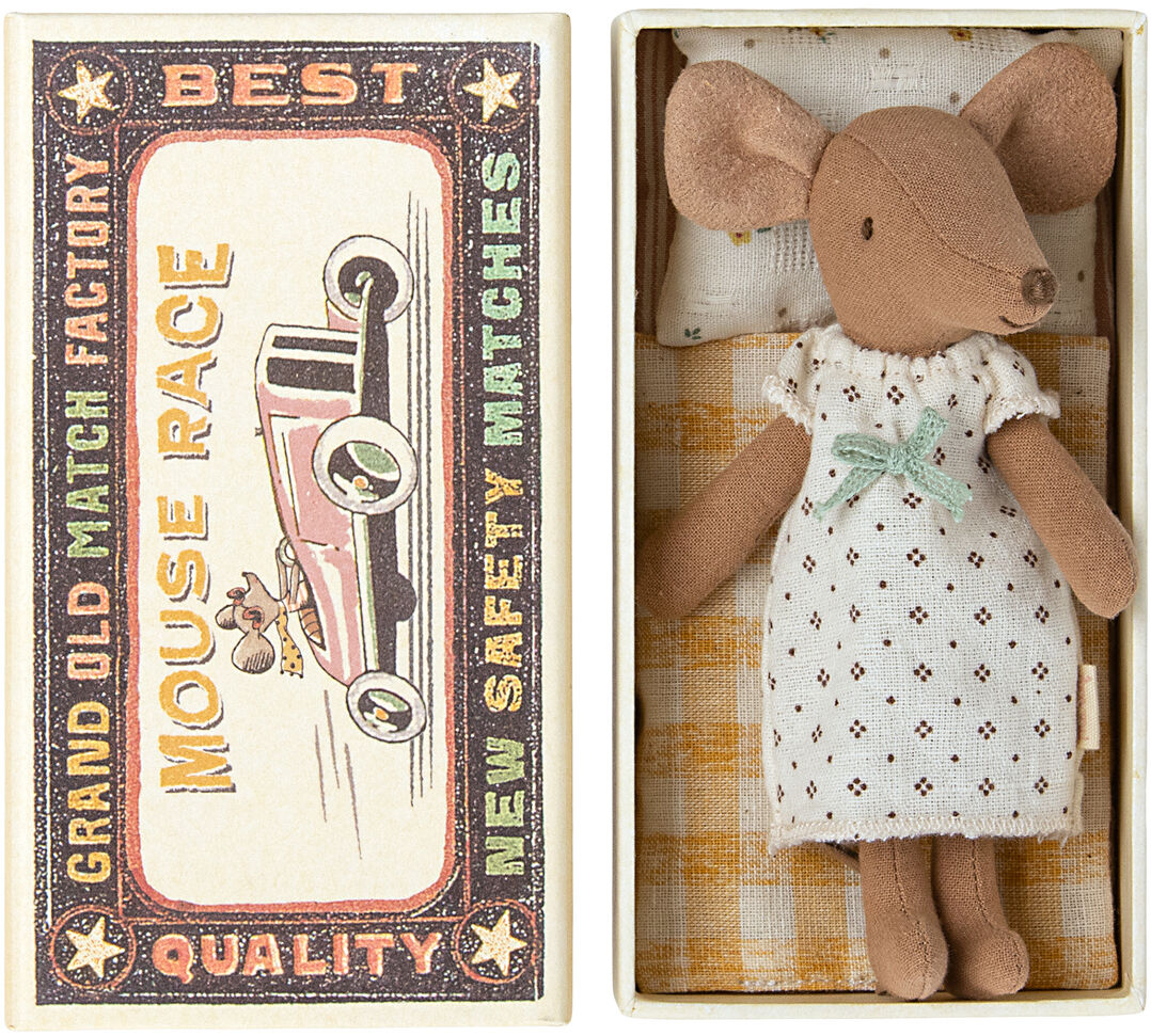 Das Bild zeigt das Spielzeug 'Große Schwester Maus' in einer Streichholzschachtel. Die Maus trägt ein weißes Kleid mit feinen Mustern und grüner Schleife. Die Schachtel ist im Vintage-Stil gestaltet, mit Aufdruck eines roten Autos, dem Schriftzug 'Mouse Race' und weiteren Beschriftungen.