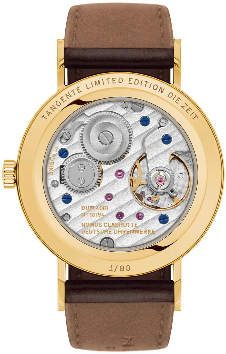 Rückansicht der NOMOS Tangente Gold 33 doré Sonderedition, limitierte Uhr mit sichtbarem Handaufzugswerk, goldfarbenem Gehäuse und braunem Shell Cordovan Lederarmband. Der Saphirglasboden zeigt das ausgefeilte Uhrwerk mit feinen Details und Nummerierung.