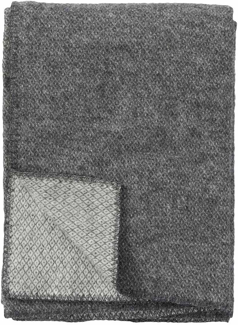 Eine graue Decke, die auf einer Seite hellgrau gemustert ist, leicht gefaltet und aus weichem Material besteht.