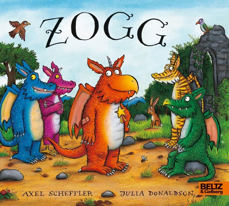 Ein Kinderbuchcover mit dem Titel 'Zogg' zeigt eine bunte Gruppe von Drachen in einer Waldlandschaft. Der zentrale Drache ist orange und trägt ein gelbes Abzeichen. Um ihn herum stehen Drachen in Blau, Gelb und Grün. Im Hintergrund sieht man Bäume, Felsen und einen Bogen. Der Titel und die Namen der Autoren, Axel Scheffler und Julia Donaldson, sind oben und unten auf dem Cover abgedruckt.