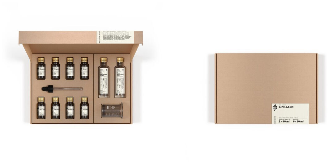 ZEIT-Sonderedition DSM »Gin Labor« Set mit mehreren kleinen Flaschen, einer Pipette und zwei größeren Flaschen in einer rechteckigen Box. Die Box hat eine beige Farbe. Das Set enthält verschiedene Aromen für Gin-Kreationen und bietet eine Experimentiermöglichkeit für Gin-Liebhaber.