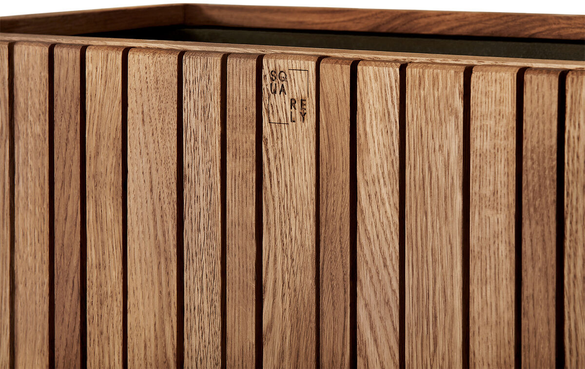 Das Bild zeigt das Pflanzgefäß »GrowWIDE«, das aus Holz gefertigt ist und eine natürliche Holzoptik aufweist. Es ist rechteckig mit vertikalen Streifenmuster.
