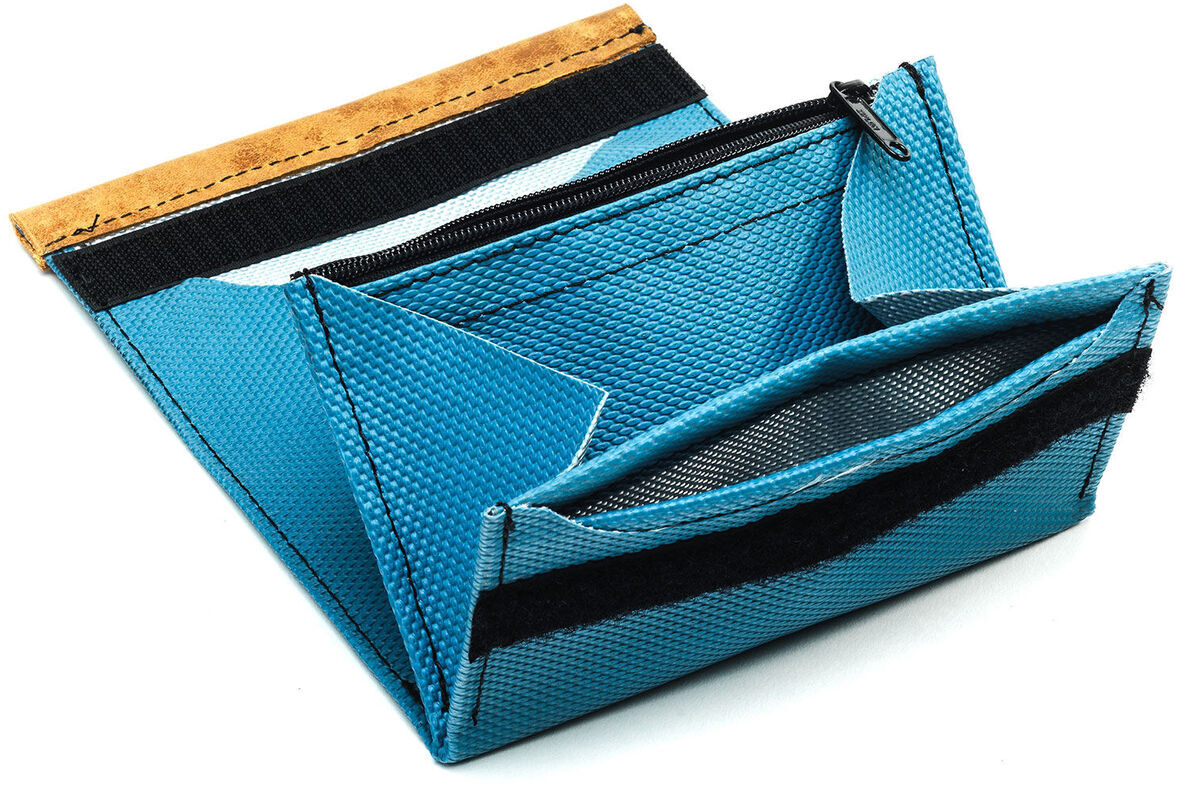 Eine blaue Geldbörse namens »Hechtrolle« aus robustem Material, die sowohl für Herren, Damen als auch Kinder geeignet ist. Sie verfügt über einen Reißverschluss und sieht minimalistisch und kompakt aus. Die Farben sind Blau, Braun und Schwarz.
