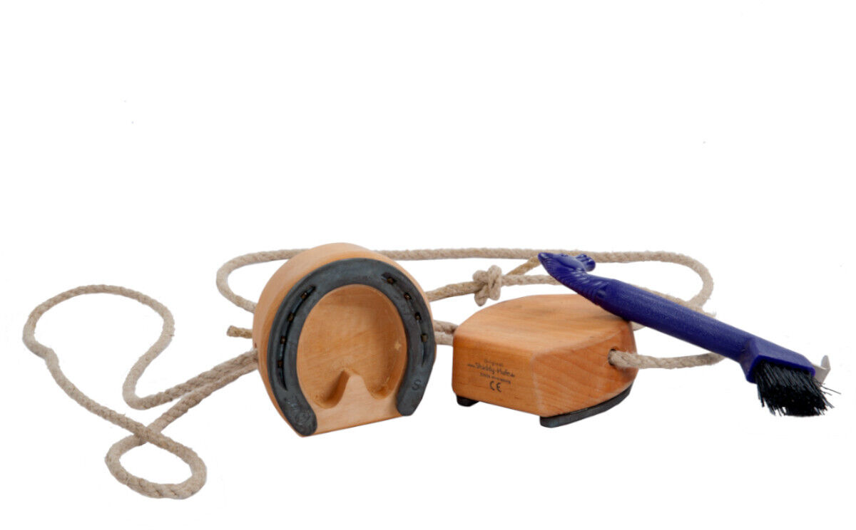 Bild von den Spielhufen »Shaddy«, die aus Holz gemacht sind. Ein Seil verbindet zwei Holzklötze, an denen Hufeisen befestigt sind. Ein blauer Pinsel liegt daneben.
