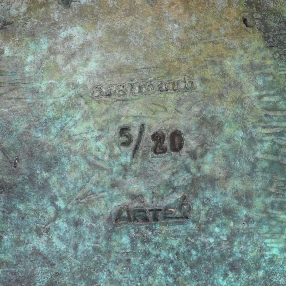 Detailansicht einer bronzefarben-patinierte Oberfläche mit sichtbaren Prägungen: 'ars mundi', '5/20' und 'ARTE'. Die strukturierte Bronze weist Farbverläufe von grün bis braun auf. Es handelt sich um einen nummerierten Kunstdruck.