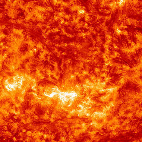 Ein abstraktes und leuchtendes Bild von Katharina Sieverding, betitelt »Die Sonne um Mitternacht schauen SDO/NASA«, 2017. Das Bild zeigt eine detaillierte Ansicht der Sonnenoberfläche in intensiven Orange- und Gelbtönen, die an Feuer und Hitze erinnern.