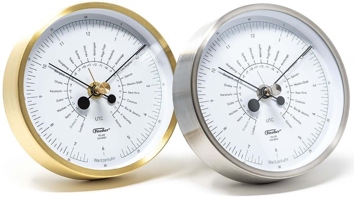 Zwei Weltzeituhren von Fischer Manufaktur, Modell POLAR, eine mit goldener und eine mit silberner Fassung, vor einem weißen Hintergrund.