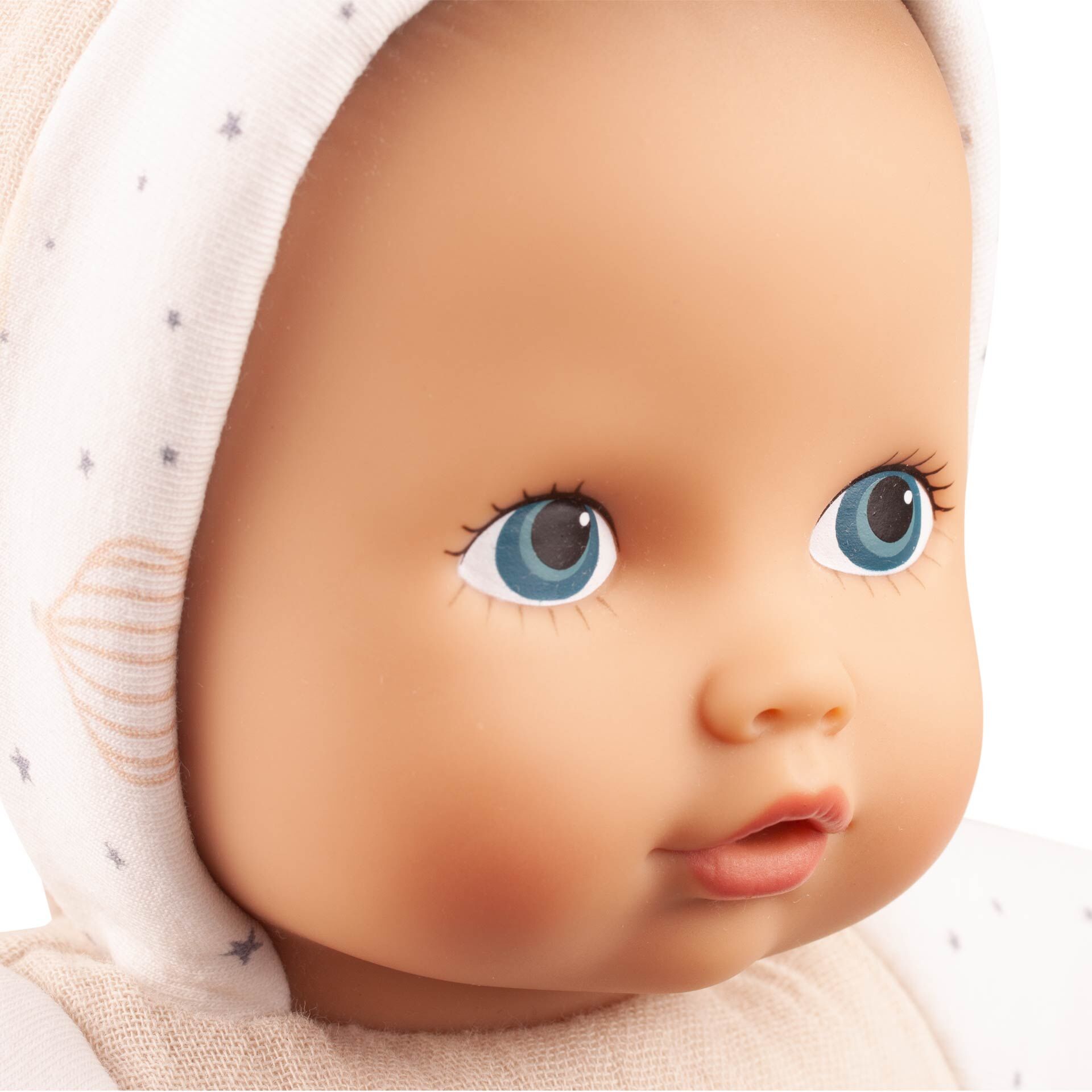 Nahaufnahme einer weichen Babypuppe mit beigem und weißem Outfit, verpackt als Geschenkbox »Baby Pure Sleep Well«. Die Puppe trägt eine Mütze mit kleinem Sternenmuster und hat große blaue Augen. Das Produkt eignet sich als liebevolles Geschenk zur Geburt oder Taufe.