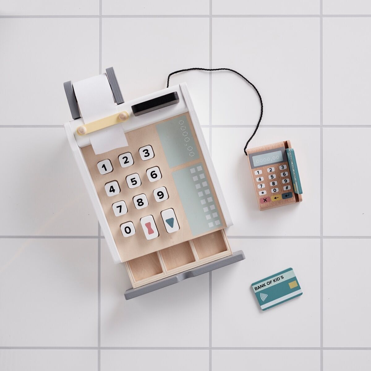 Eine Kasse aus Holz mit Zahlenknöpfen, einer kleinen Rechenschieber und einer Spielkarte, auf einem weißen Hintergrund platziert.