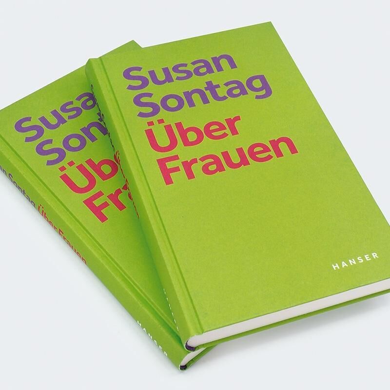 Zwei Bücher mit grünem Einband und dem Titel 'Über Frauen' von Susan Sontag in großen lila und roten Buchstaben. Der Verlag Hanser wird in weißer Schrift auf dem Buchcover erwähnt.