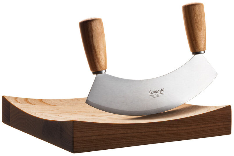 Das Wiegemesser »Soul« besteht aus einer gebogenen Edelstahlklinge mit zwei Holzgriffen, stehenderweise auf einem dazugehörigen, rechteckigen Schneidebrett. Die Klinge ist scharf und die Griffe ergonomisch gestaltet.