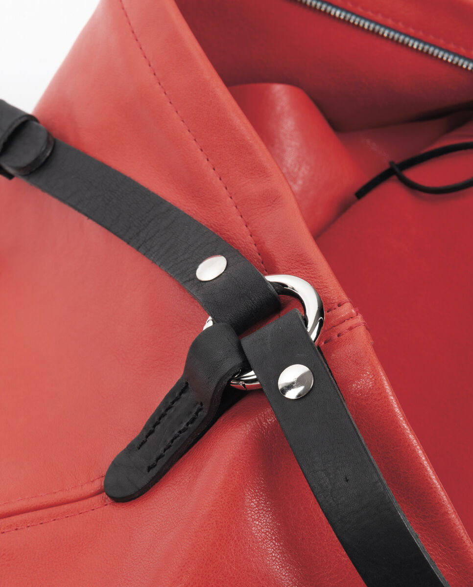 Nahaufnahme einer roten Ledertasche »Nabuko« mit schwarzen Trageriemen und silbernen Details wie einem Reißverschluss und einem Ringverschluss. Die Tasche wirkt elegant und hochwertig verarbeitet.