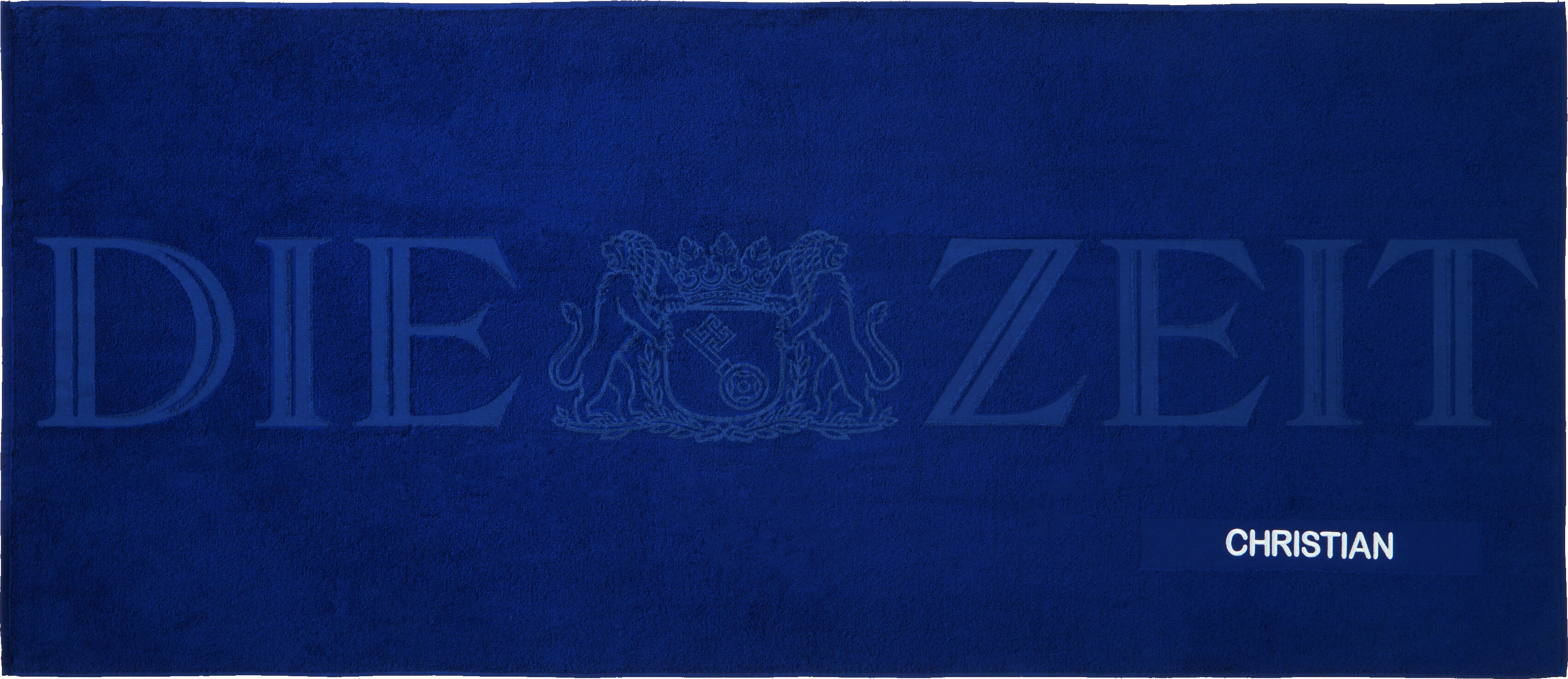 Blaues Badetuch mit weißem Streifen, darauf der Text 'DIE ZEIT' und das Wappen von DIE ZEIT. Der Name CHRISTIAN ist in weiß gedruckt. Hochwertiges, personalisiertes Handtuch für verschiedene Anlässe.