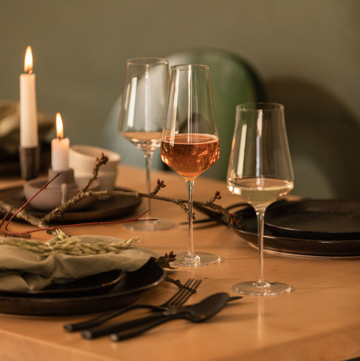 Zwei Champagnergläser aus dem 2er-Set »DUO« stehen auf einem gedeckten Tisch mit Kerzen und elegantem Geschirr. Perfekt für besondere Anlässe und Feierlichkeiten.