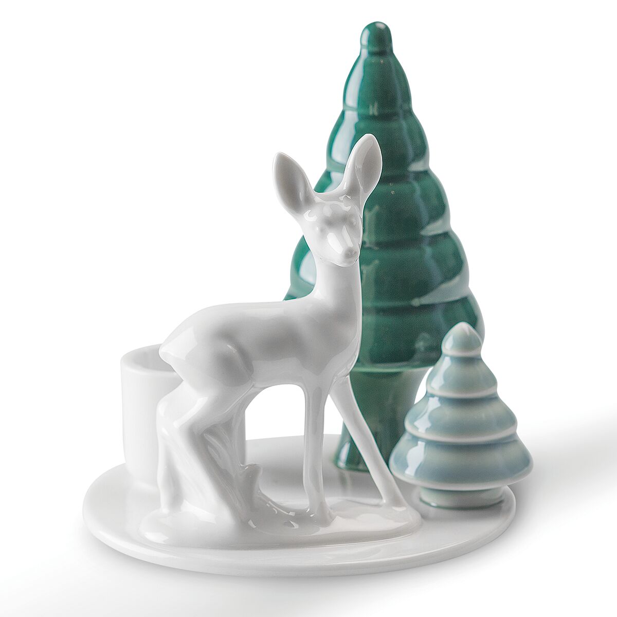 Detailreiche Porzellanfigur: Ein weißes Bambi steht auf einer runden Platte, flankiert von zwei stilisierten Tannenbäumen in unterschiedlichen Grüntönen. Integriert ist eine Halterung für eine Kerze. Die Szene vermittelt winterliche, festliche Stimmung und ist handgefertigt.