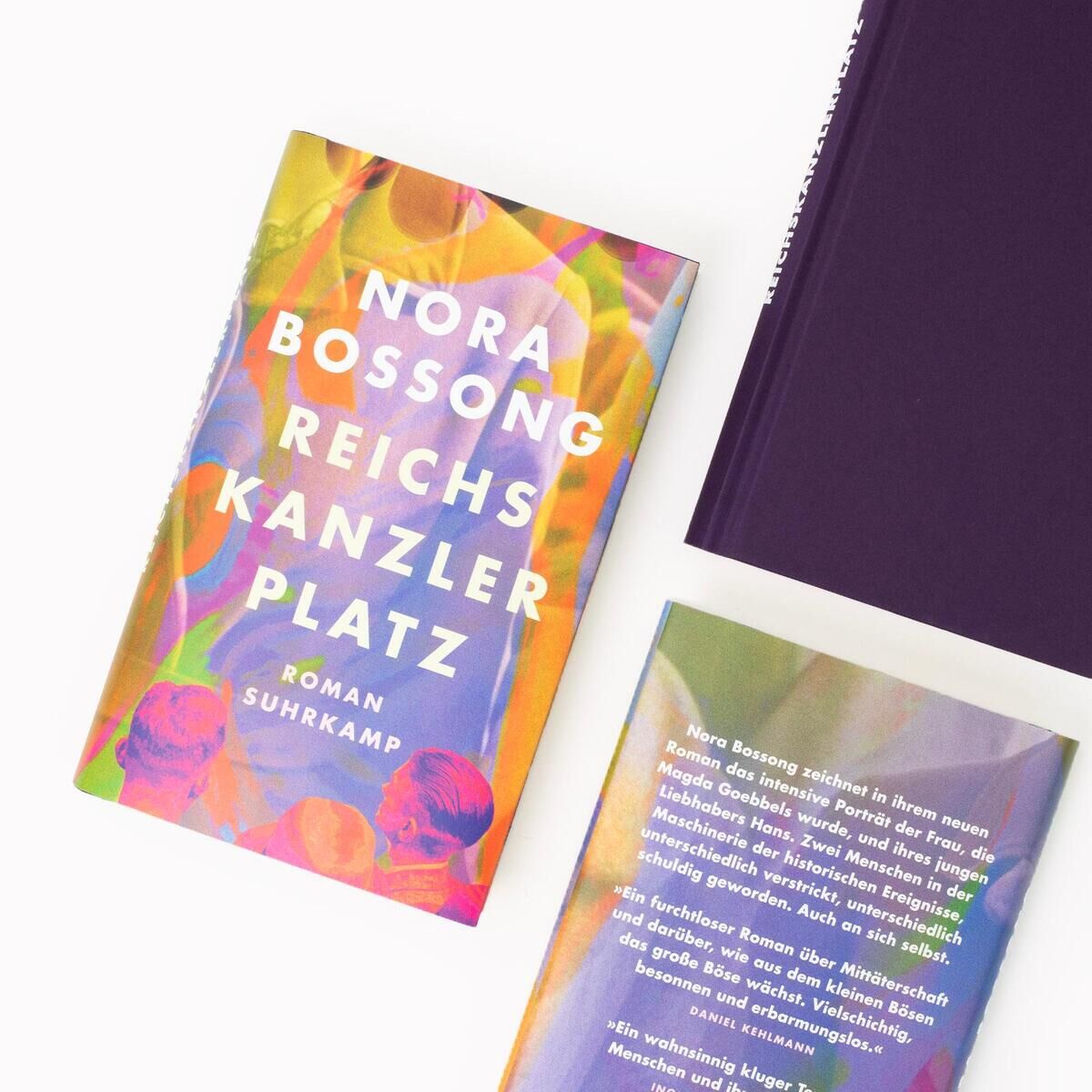 Das Bild zeigt die Vorder- und Rückseite des Buches 'Reichskanzlerplatz' von Nora Bossong. Das farbenfrohe Buchcover enthält die Farben Lila, Orange, Gelb, Grün und Blau. Das Buch liegt auf einer weißen Oberfläche.