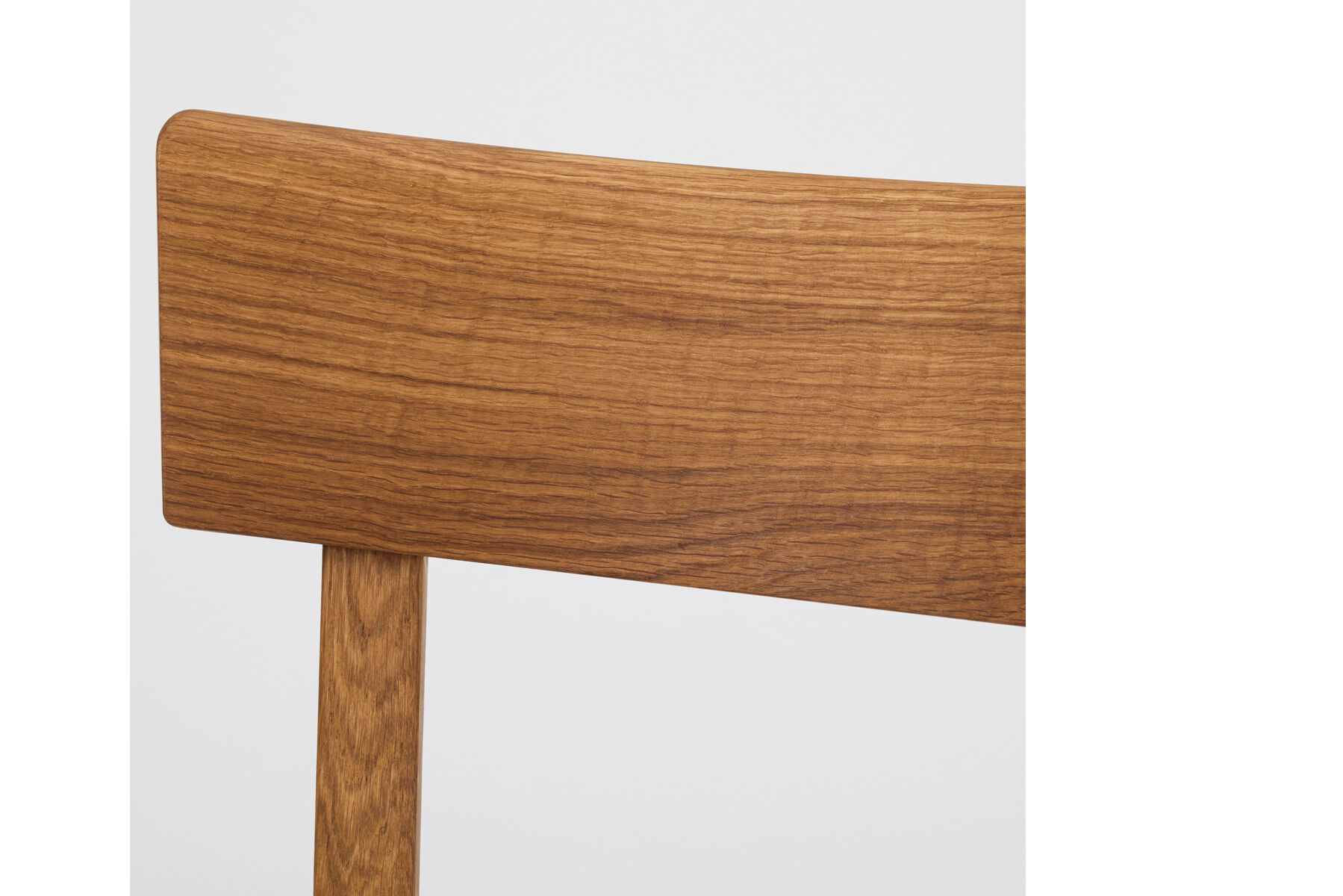 Detailaufnahme einer Stuhllehne aus geöltem Eichenholz im minimalistischen Stil vor neutralem Hintergrund. Der Stuhl ist Teil der ZEIT Sonderedition 'Frankfurter Küchenstuhl'.