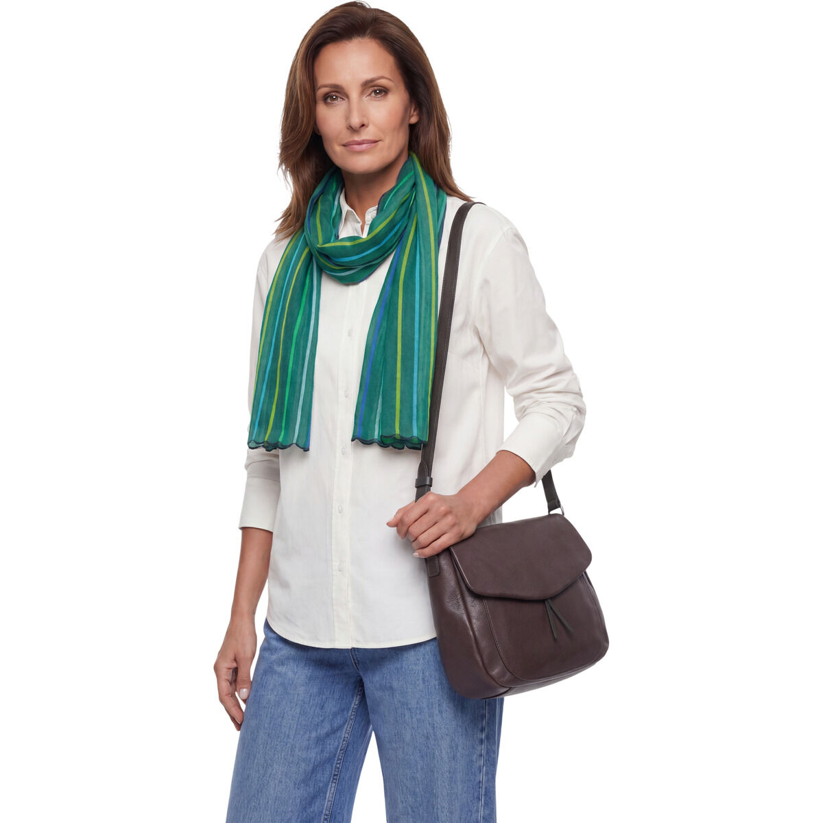 Frau mit langem, handgewebtem Leinenschal der Marke Ulrike Isensee in Grün mit feinen blauen Streifen. Sie trägt eine weiße Bluse, eine dunkelbraune Umhängetasche und Jeans. Der Schal wirkt leicht und elegant, das Outfit ist casual und stilvoll kombiniert.