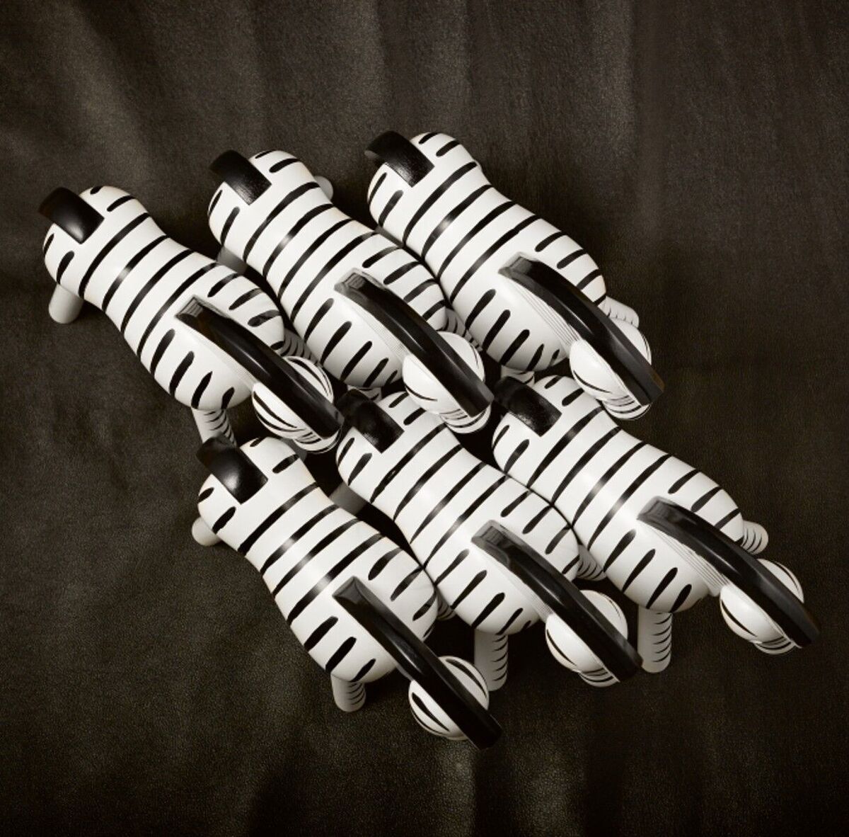 Mehrere Holzfiguren in Form eines Zebras von Kay Bojesen, mit schwarzen Streifen auf weißem Hintergrund, angeordnet auf einer dunklen Oberfläche.