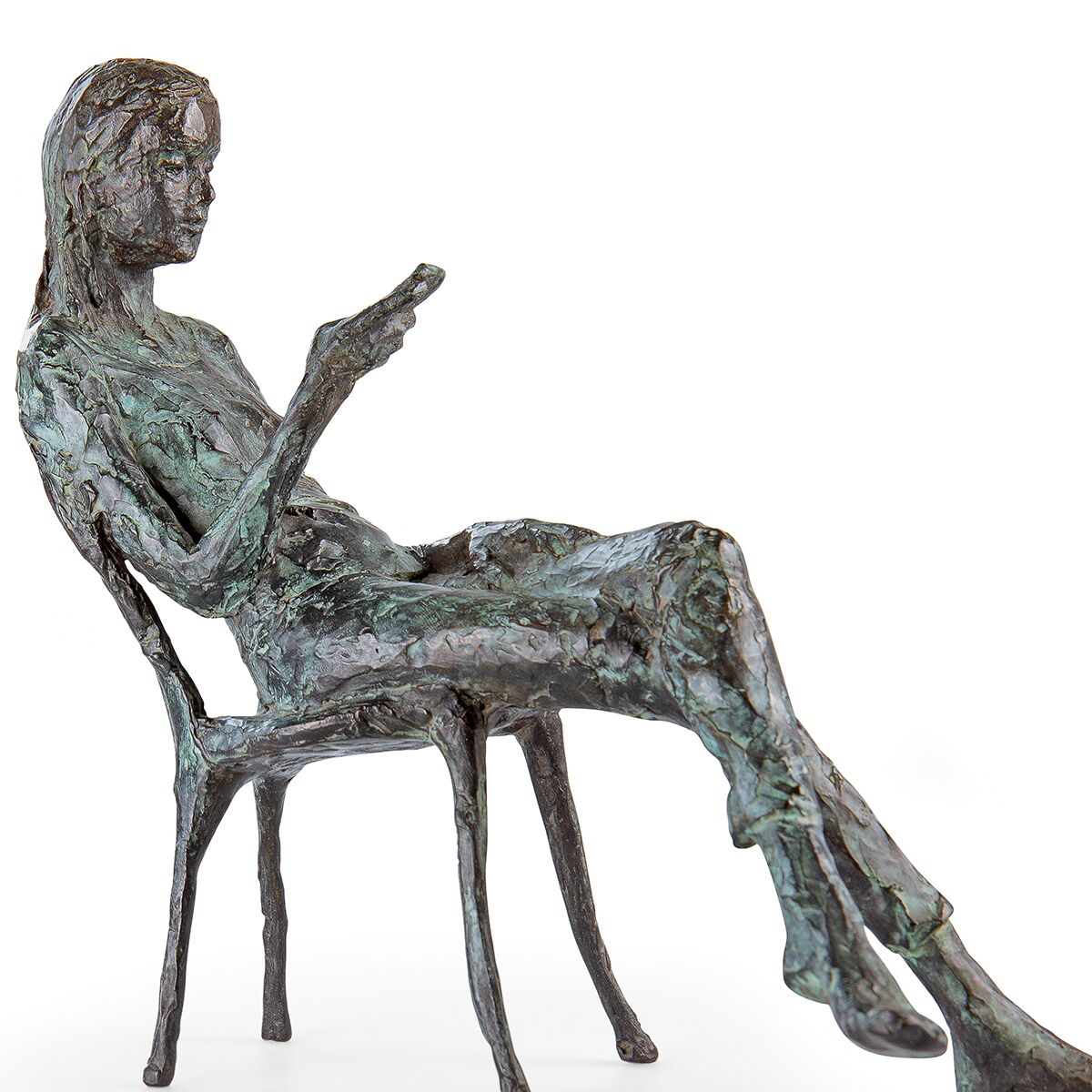 Filigrane Bronzeskulptur einer sitzenden Frau auf einem Stuhl, vertieft in Gedanken mit Blick nach vorne oder auf ein Objekt in ihrer Hand. Die Oberfläche zeigt grün-graue Patina-Effekte und eine strukturierte, künstlerisch gestaltete Ausführung. Zwei Stuhlbeine sowie Beine der Figur sind lang und schlank ausgebildet.